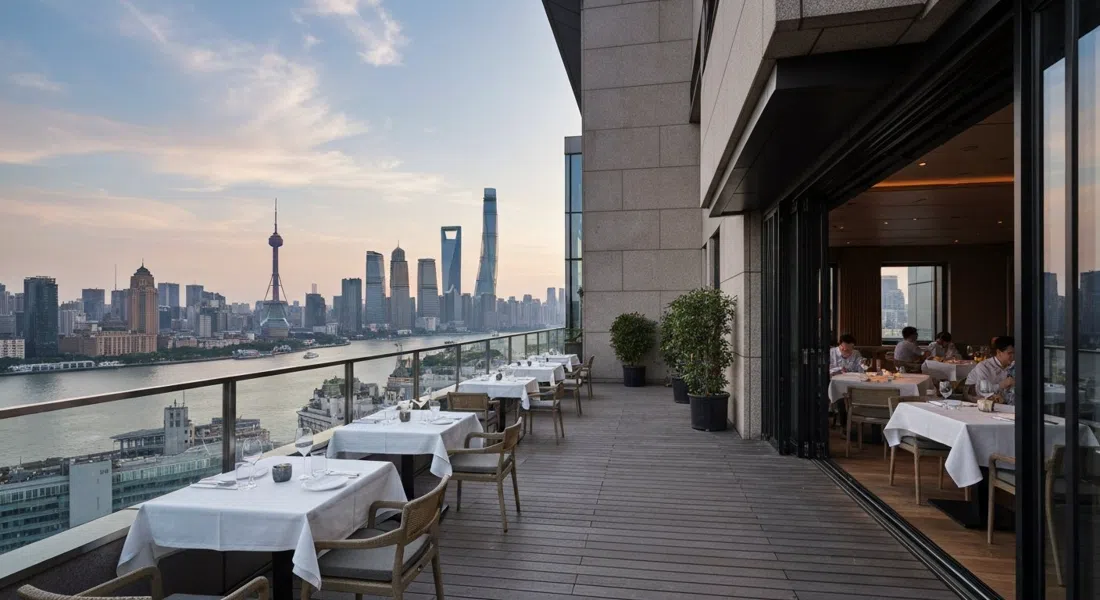 La terraza y el comedor de Mr & Mrs Bund en el sexto piso de Bund 18, luz vespertina sobre el Huangpu con reflejos del horizonte al fondo