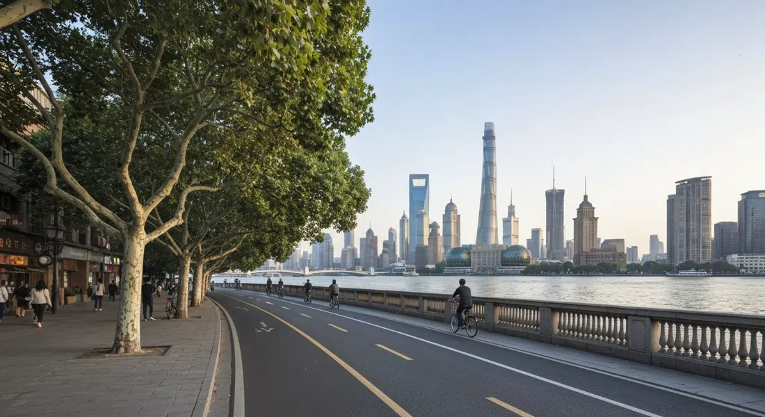 el paseo ribereño de Xuhui en el West Bund con plátanos de sombra, carriles bici, amplias balaustradas y las torres de Pudong difusas al otro lado del Huangpu a la luz del atardecer